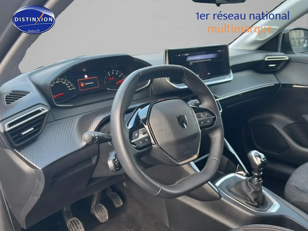 Vue intérieure côté conducteur du tableau de bord et volant de la Peugeot 208 gris Artense avec boîte manuelle.