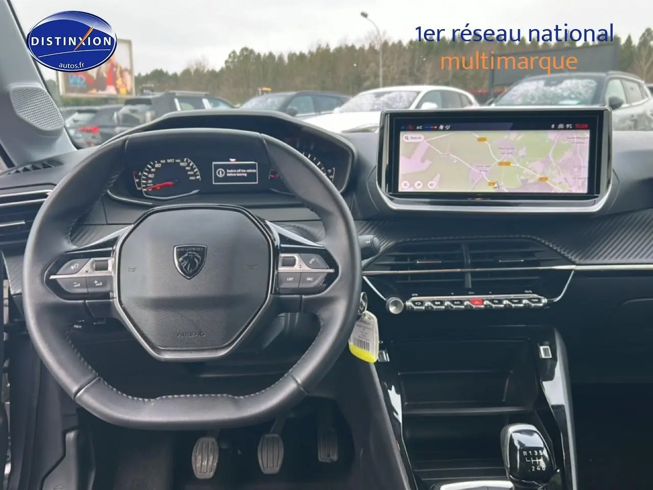 Vue intérieure centrée sur le volant Peugeot et l’écran tactile du tableau de bord d’une 208 gris artense.