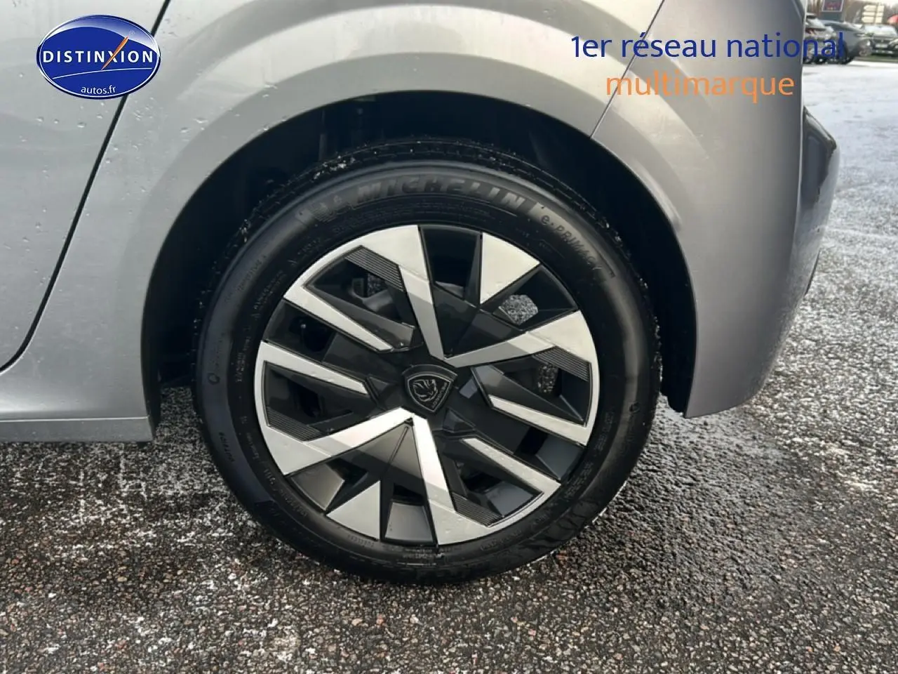 Gros plan sur la roue arrière droite d'une Peugeot 208 gris artense avec jante alliage au design géométrique.