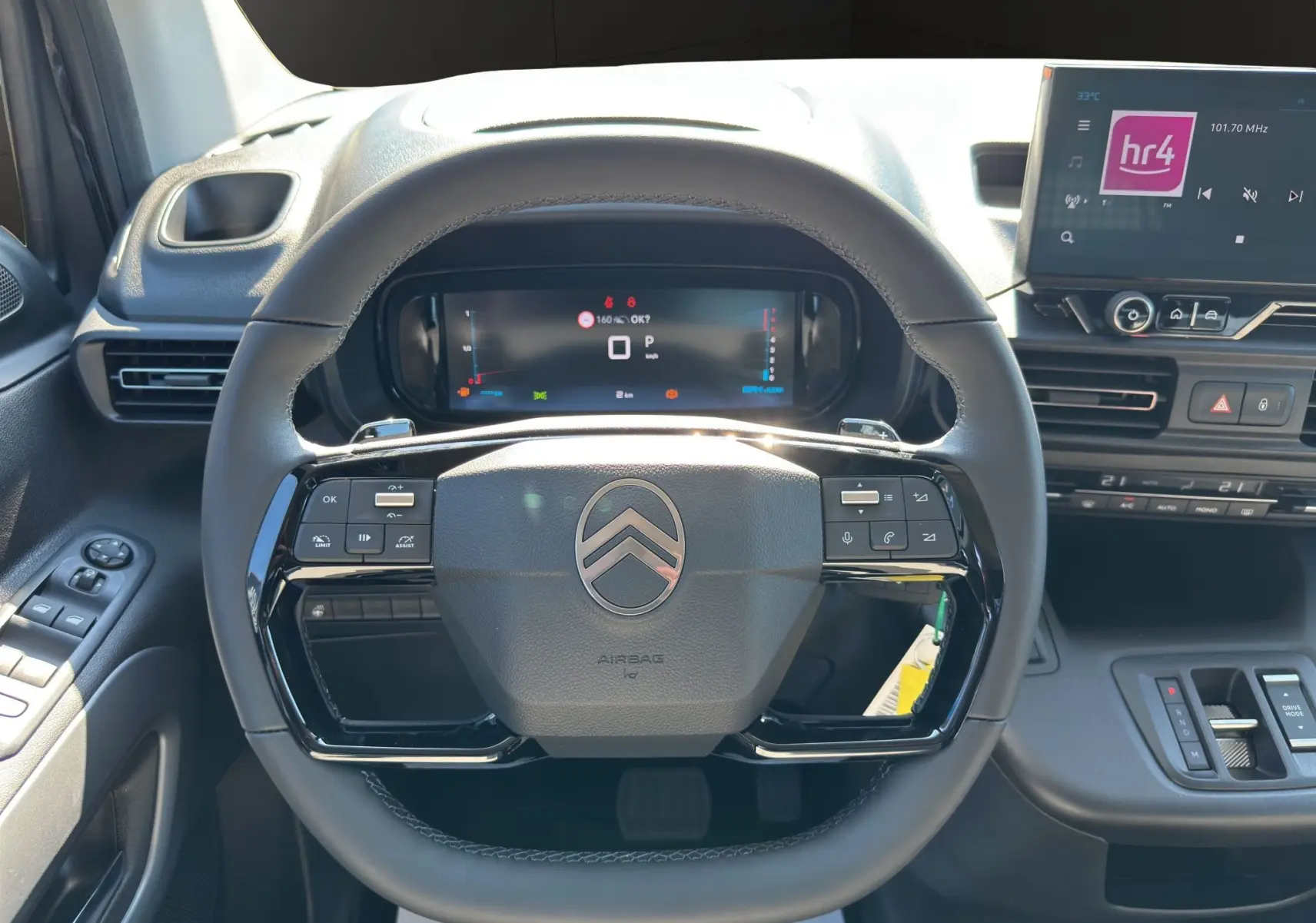Vue intérieure centrée sur le volant noir du Citroën Berlingo 2025 avec tableau de bord numérique et écran tactile.