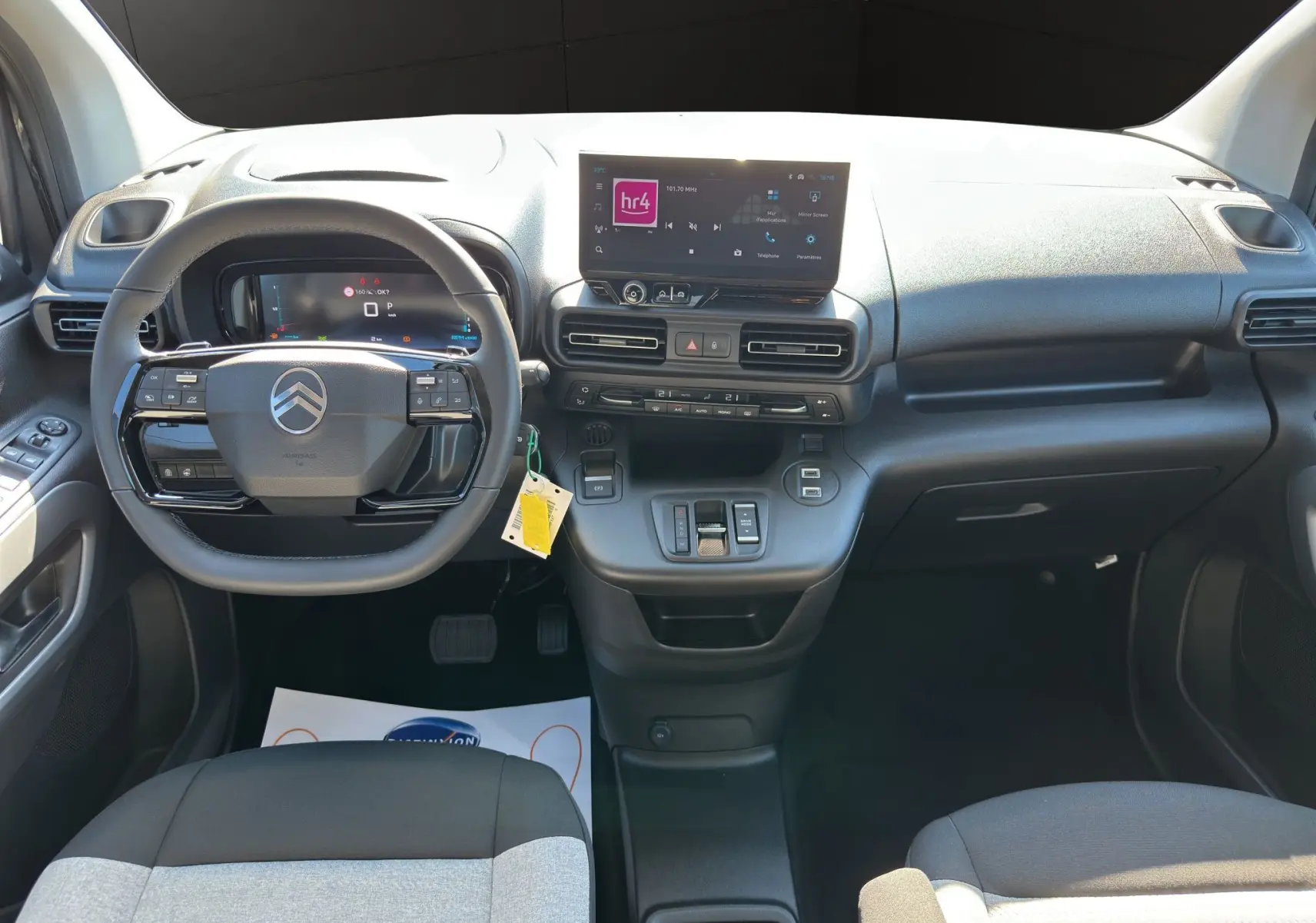 Vue intérieure avant du Citroën Berlingo 2025, tableau de bord noir avec écran tactile et volant multifonction.