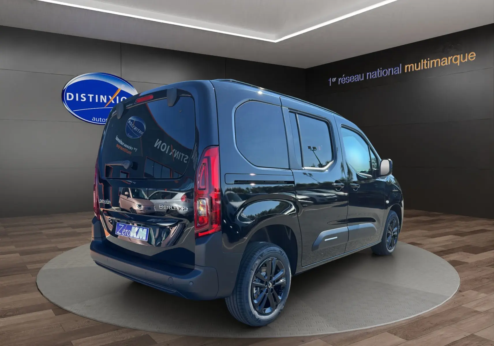 Vue 3/4 arrière droite d'un Citroën Berlingo noir avec vitres teintées et jantes alliage 16 pouces dans un showroom.