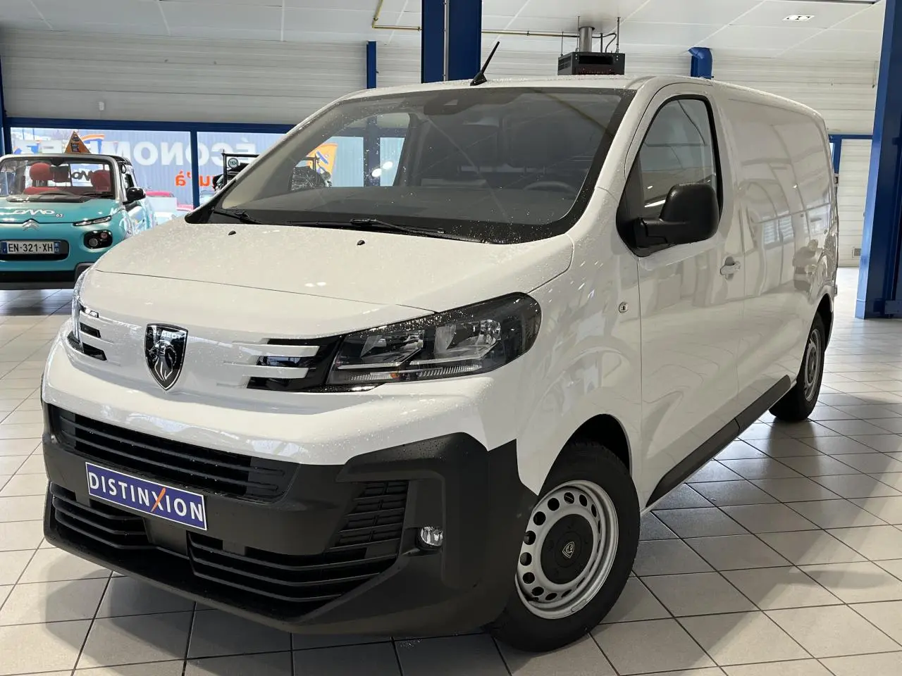Vue 3/4 avant droit d’un Peugeot Expert Fourgon blanc avec boucliers noirs et jantes tôles grises en showroom.