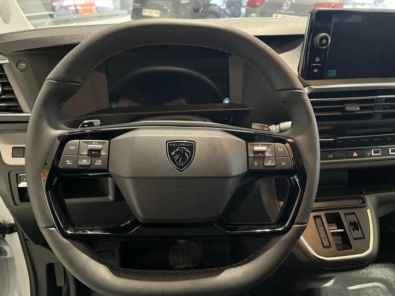 Vue rapprochée du volant en cuir noir du Peugeot Expert Fourgon 2024 avec commandes intégrées et tableau de bord numérique.
