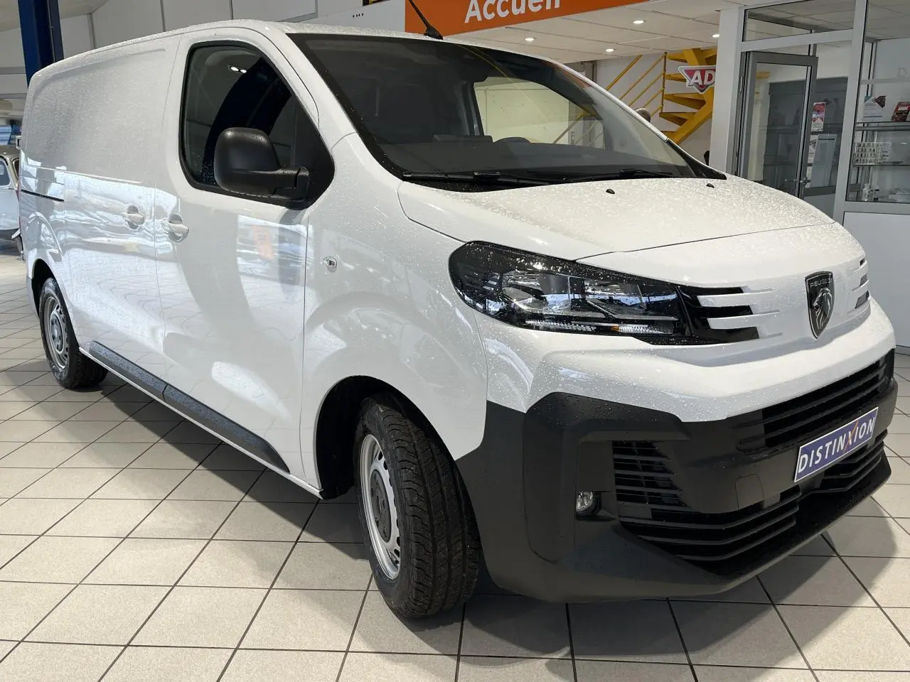 Peugeot Expert Fourgon blanc en 3/4 avant droit, avec boucliers noirs et roues tôles grises en showroom.