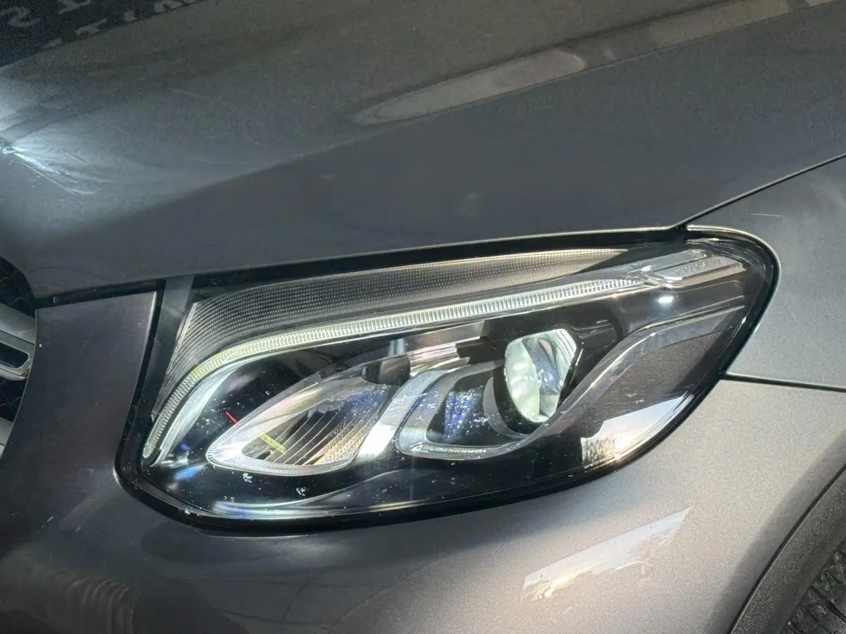 Gros plan sur le phare avant droit d’un Mercedes GLC 250 Fascination 4Matic gris foncé, montrant les détails LED.