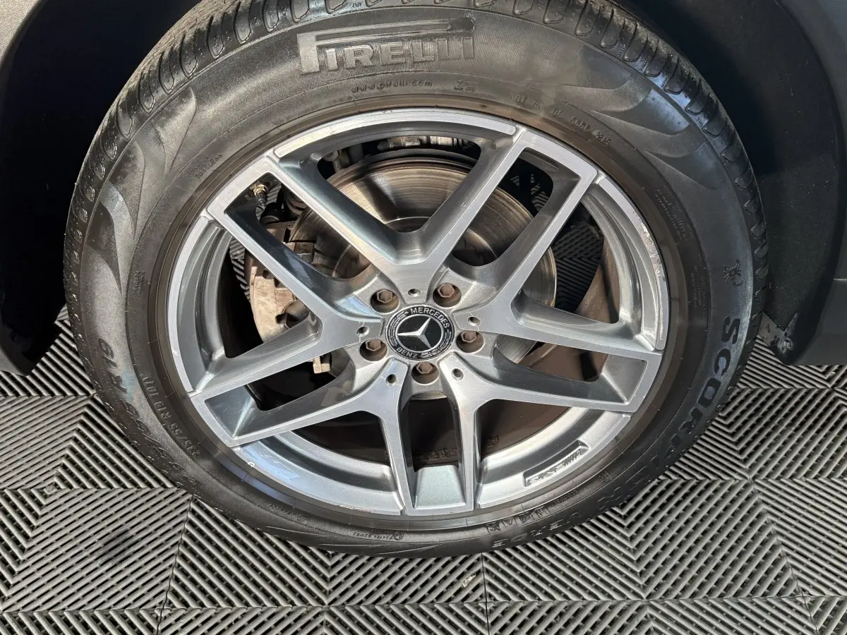 Gros plan sur la jante alliage argentée avec logo Mercedes d’un Mercedes GLC 250 Fascination 2019 gris foncé.