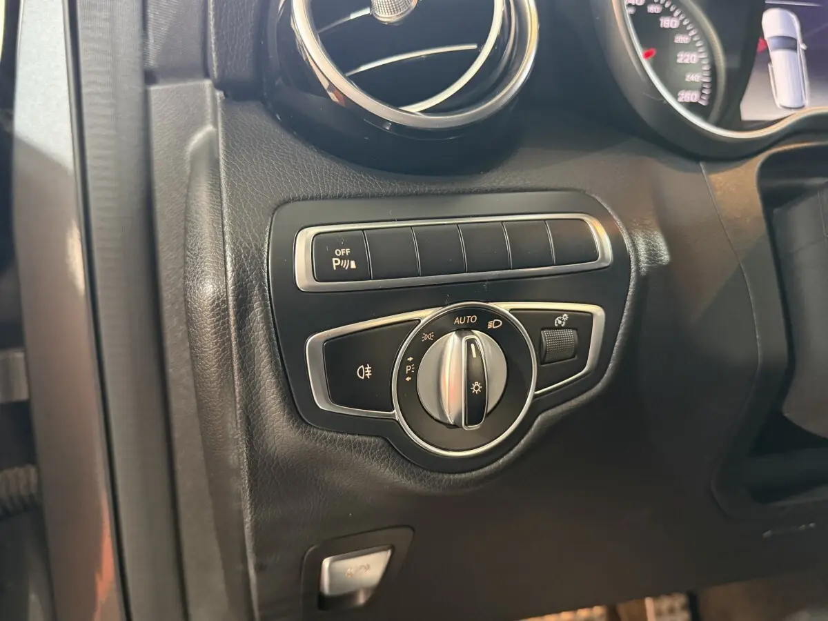 Détail du tableau de bord noir du Mercedes GLC 250 Fascination 2019 montrant la commande des phares et l'activation du stationnement.