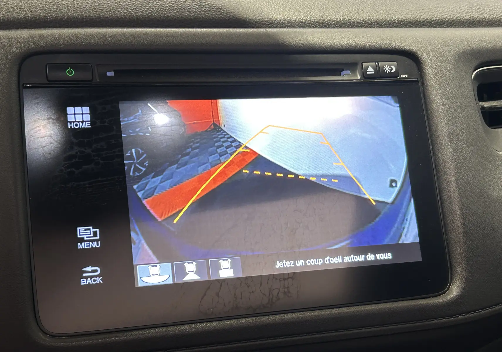 Écran de caméra de recul du Honda HR-V bleu, affichant les lignes de guidage et un sol carrelé en arrière-plan.