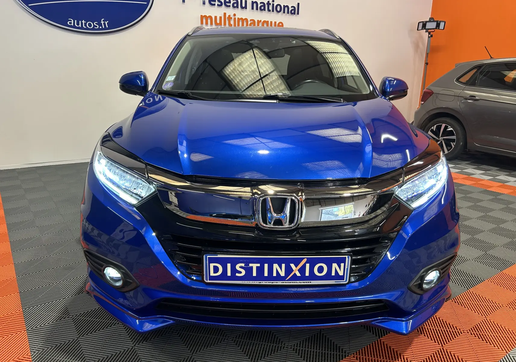 Vue avant d’un Honda HR-V bleu 2020 avec phares LED allumés et calandre noire brillante dans un showroom.