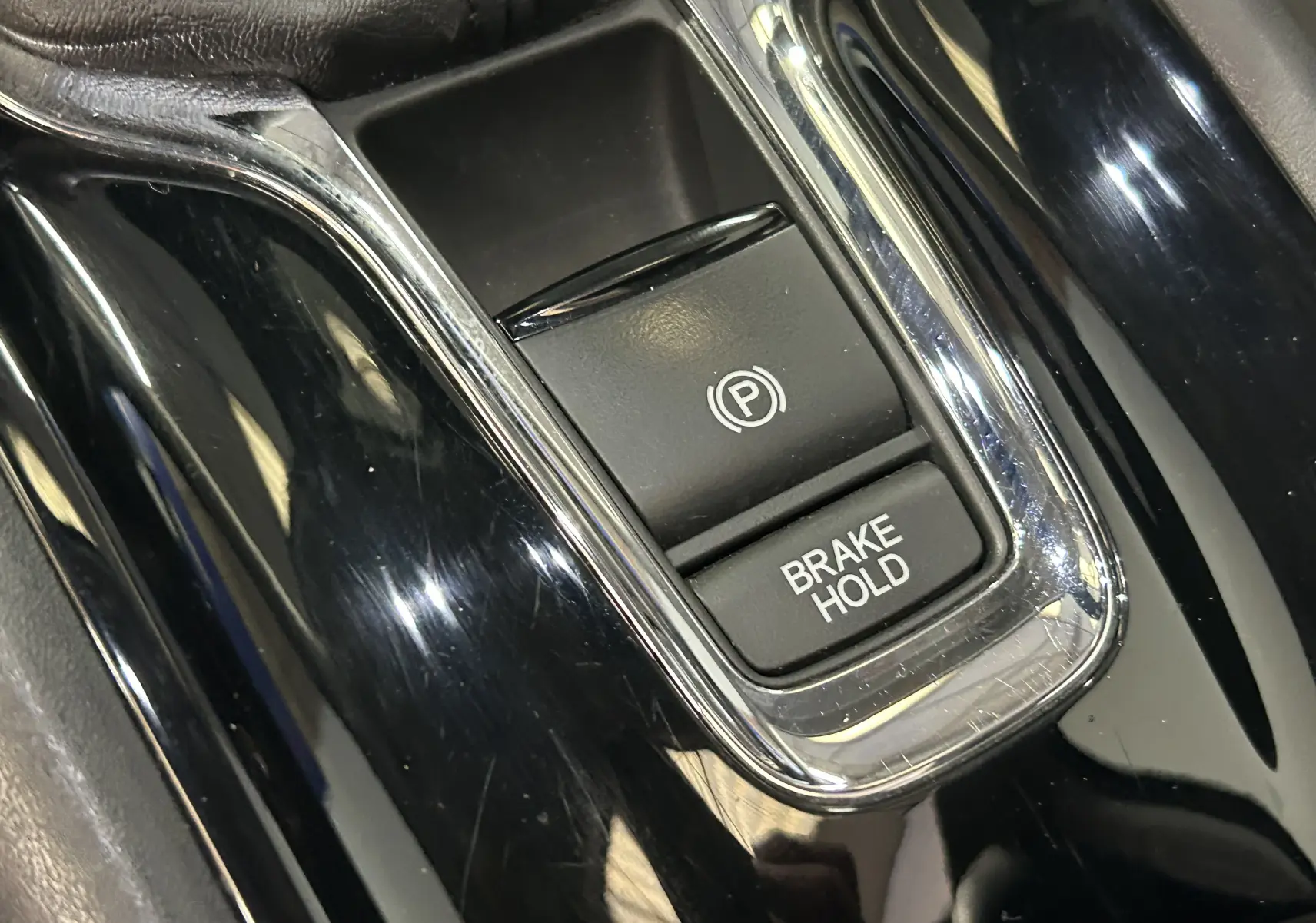 Gros plan sur les boutons de frein de stationnement électrique et Brake Hold dans l'habitacle noir brillant du Honda HR-V 2020.
