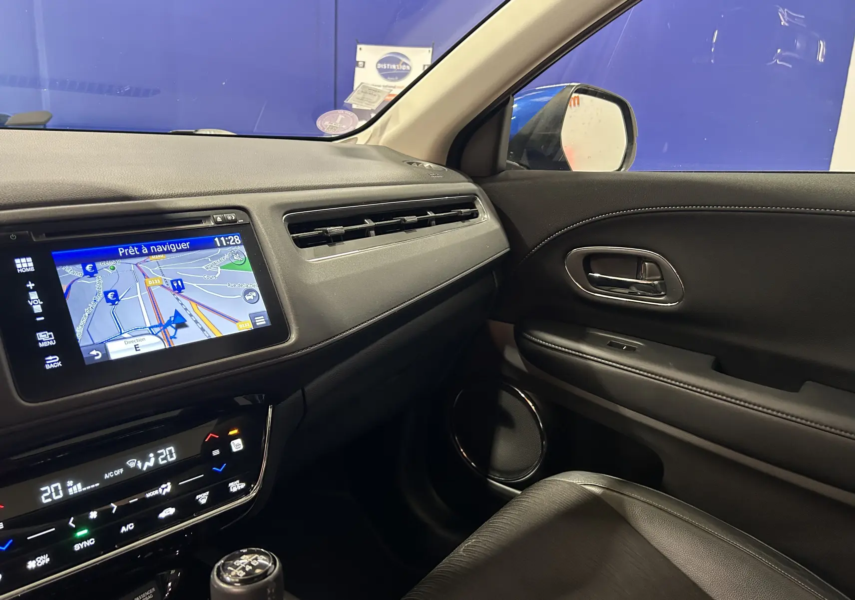 Vue intérieure côté passager du tableau de bord et de la portière noire du Honda HR-V bleu, avec écran de navigation allumé.
