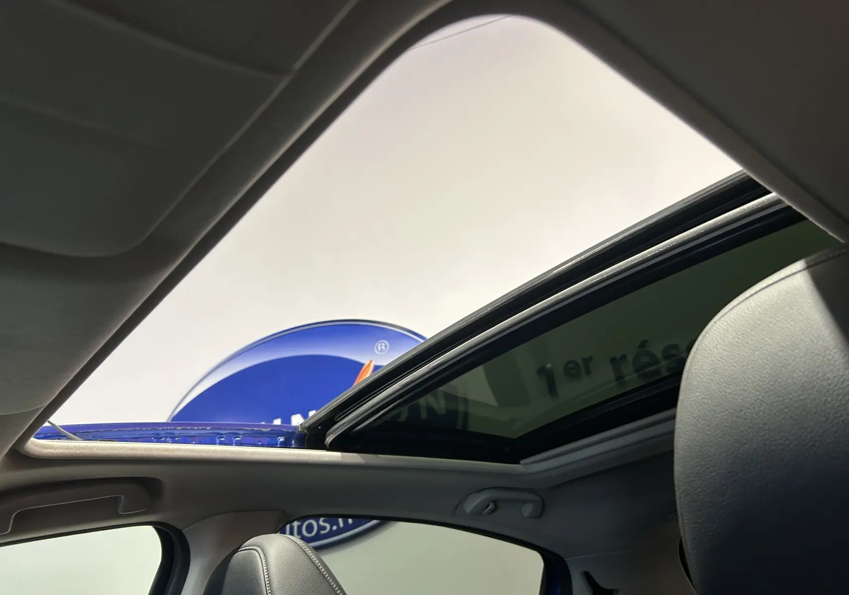 Vue intérieure du toit ouvrant ouvert du Honda HR-V bleu, mettant en valeur la sellerie cuir et la lumière naturelle.