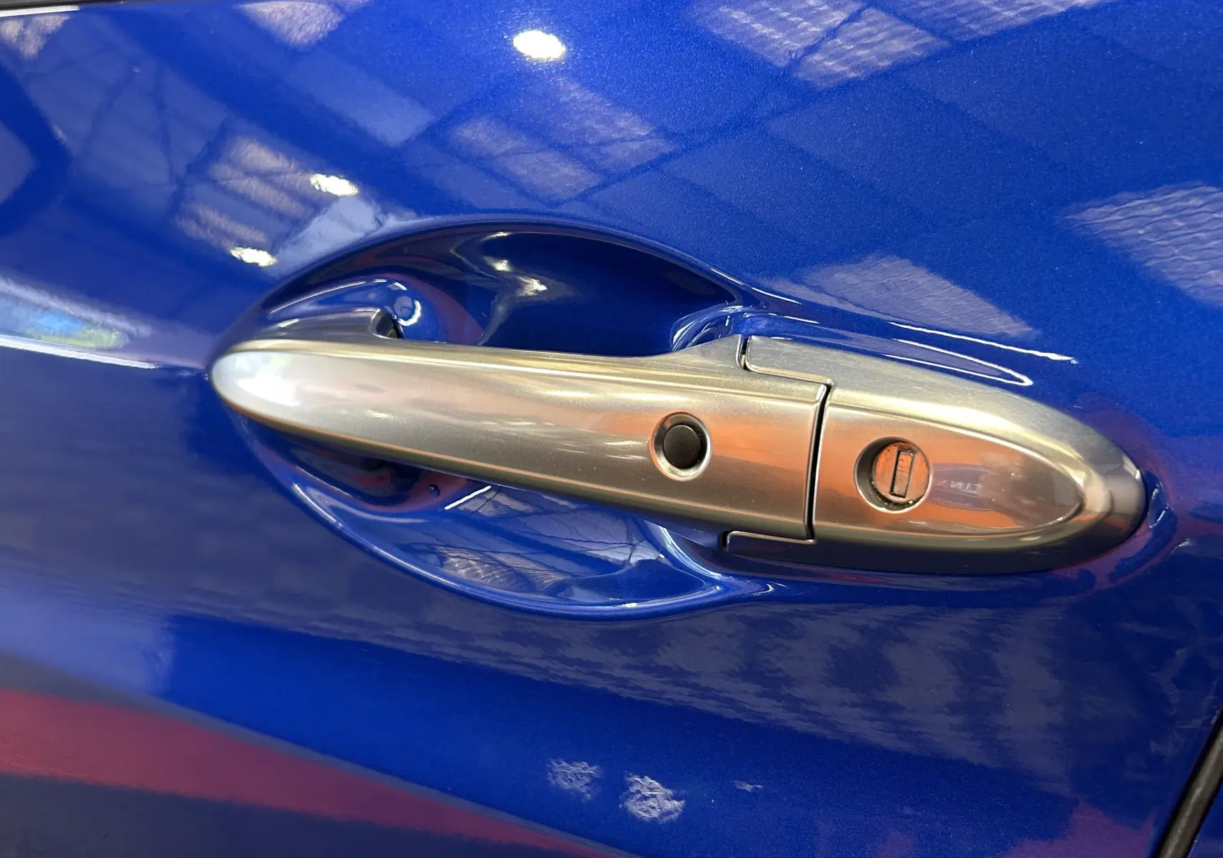 Poignée de porte avant droite chromée sur Honda HR-V bleu 2020, avec serrure et bouton de déverrouillage.