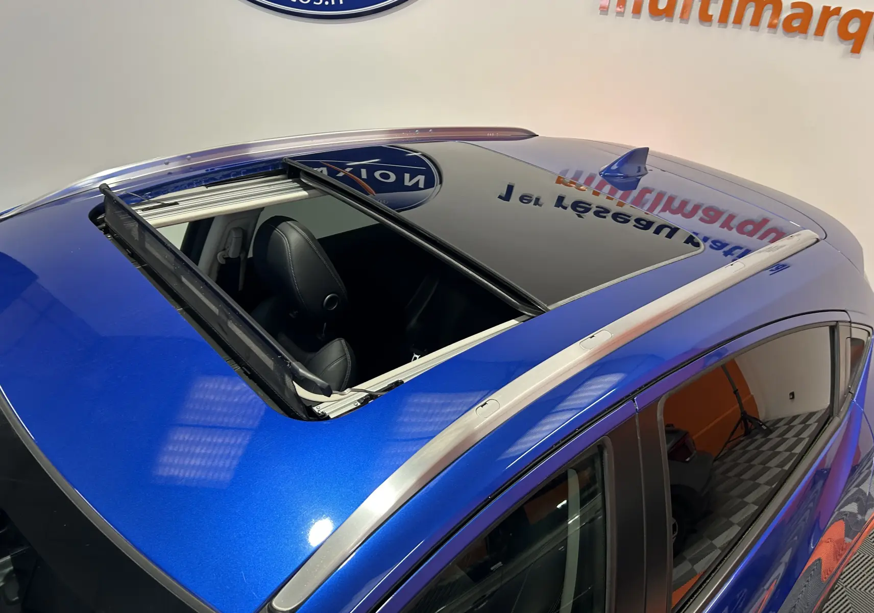 Vue plongeante sur le toit ouvrant ouvert d'un Honda HR-V bleu, mettant en valeur les barres de toit argentées.