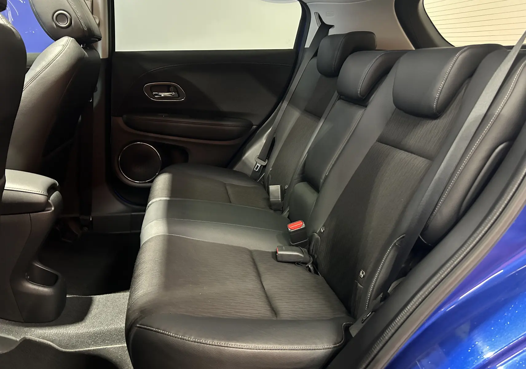 Vue intérieure côté droit des sièges arrière en cuir noir du Honda HR-V bleu, avec portière ouverte.