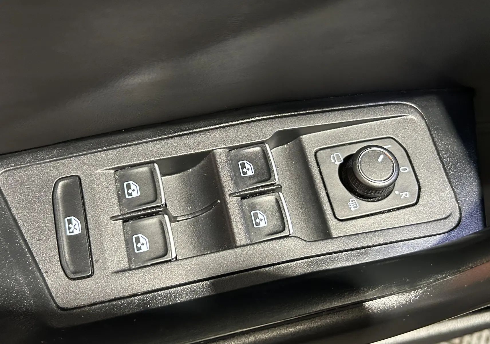 Panneau de commandes des vitres électriques et réglage des rétroviseurs dans un Volkswagen T-Roc noir, vue en plongée.