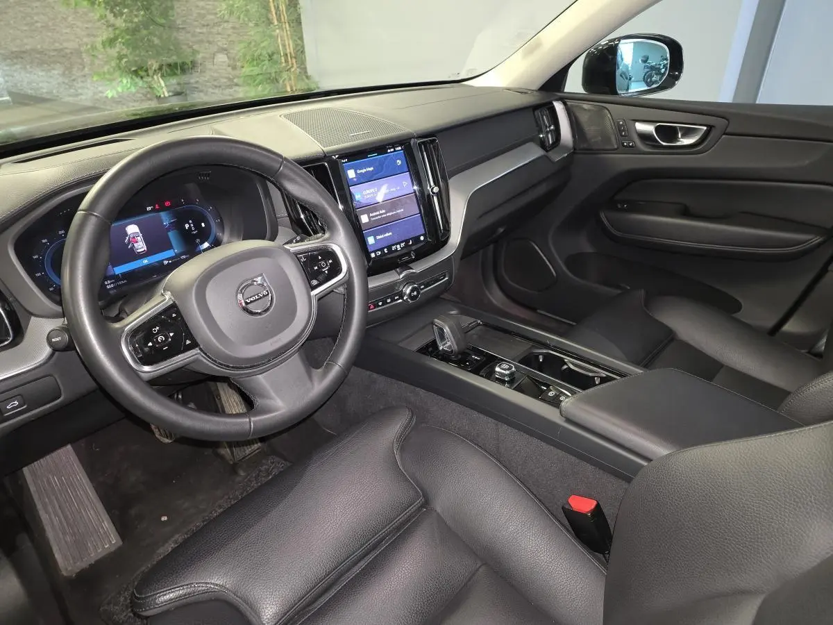 Vue intérieure côté conducteur du Volvo XC60 noir, avec tableau de bord digital et écran tactile central vertical.