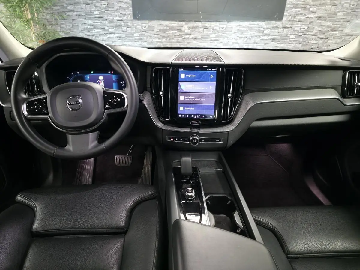 Intérieur noir du Volvo XC60 2023, vue frontale du tableau de bord avec écran tactile vertical et volant multifonction.