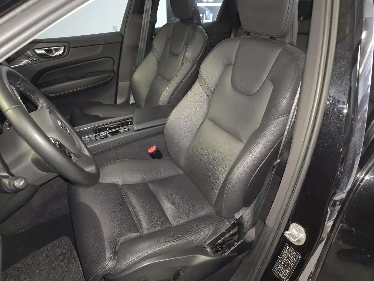 Vue intérieure côté conducteur du Volvo XC60 noir 2023, sièges cuir noirs et console centrale visible.
