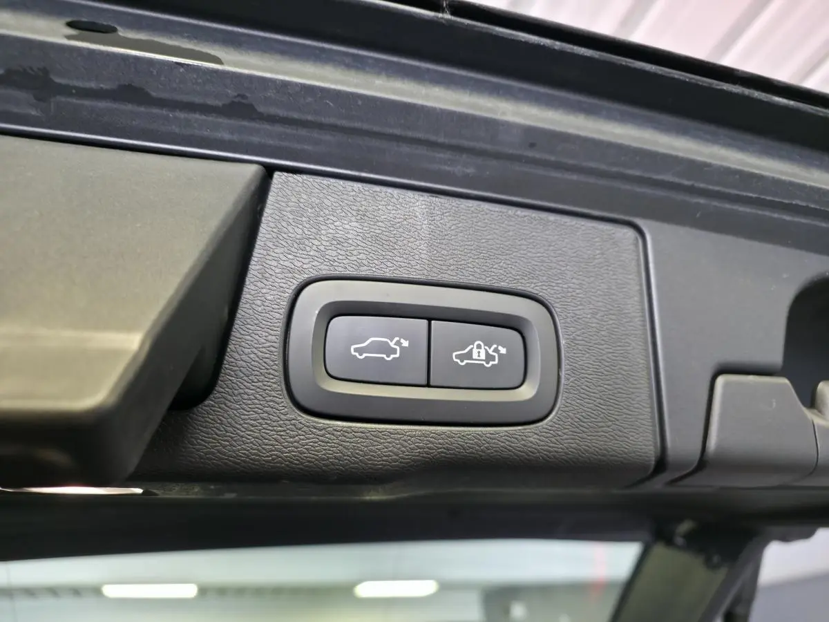 Gros plan sur les boutons d'ouverture et de verrouillage du hayon électrique du Volvo XC60 noir.