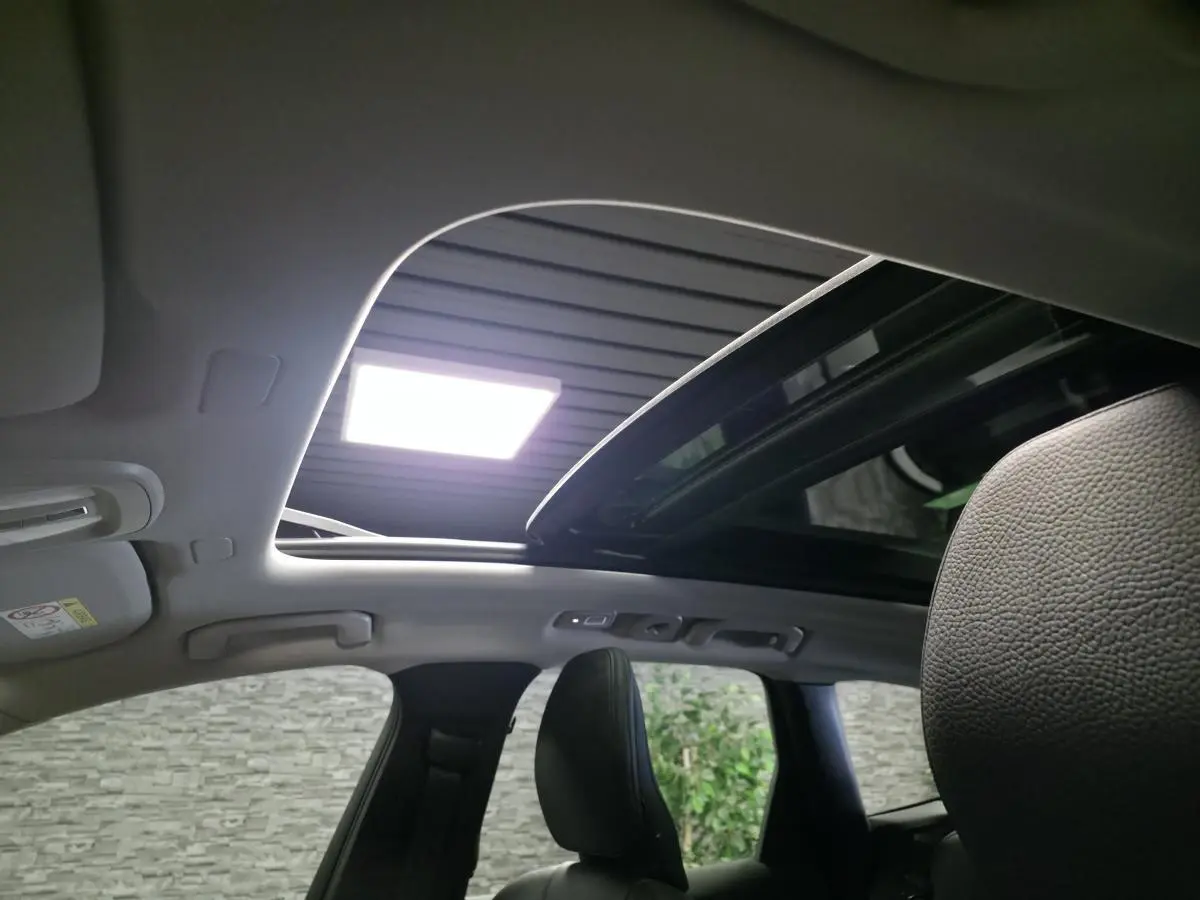 Toit ouvrant panoramique ouvert vu de l'intérieur arrière du Volvo XC60 noir, avec ciel de toit gris clair.