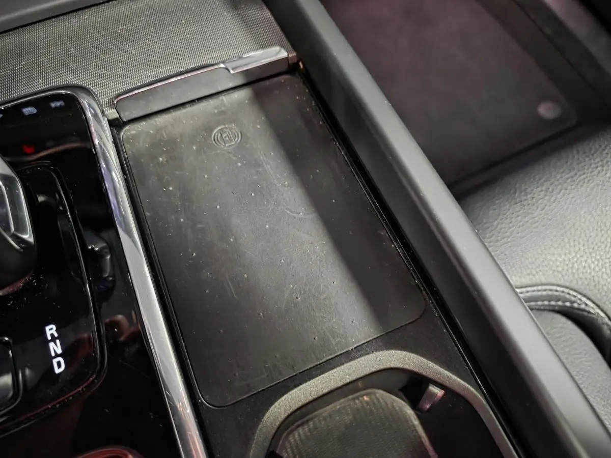 Détail de la console centrale noire du Volvo XC60 2023 avec chargeur sans fil et levier de vitesse automatique.