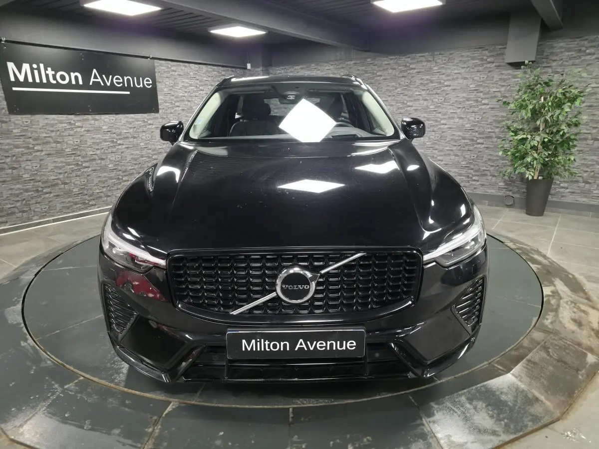 Vue de face du Volvo XC60 noir métallisé avec calandre et inserts noirs laqués dans un showroom.