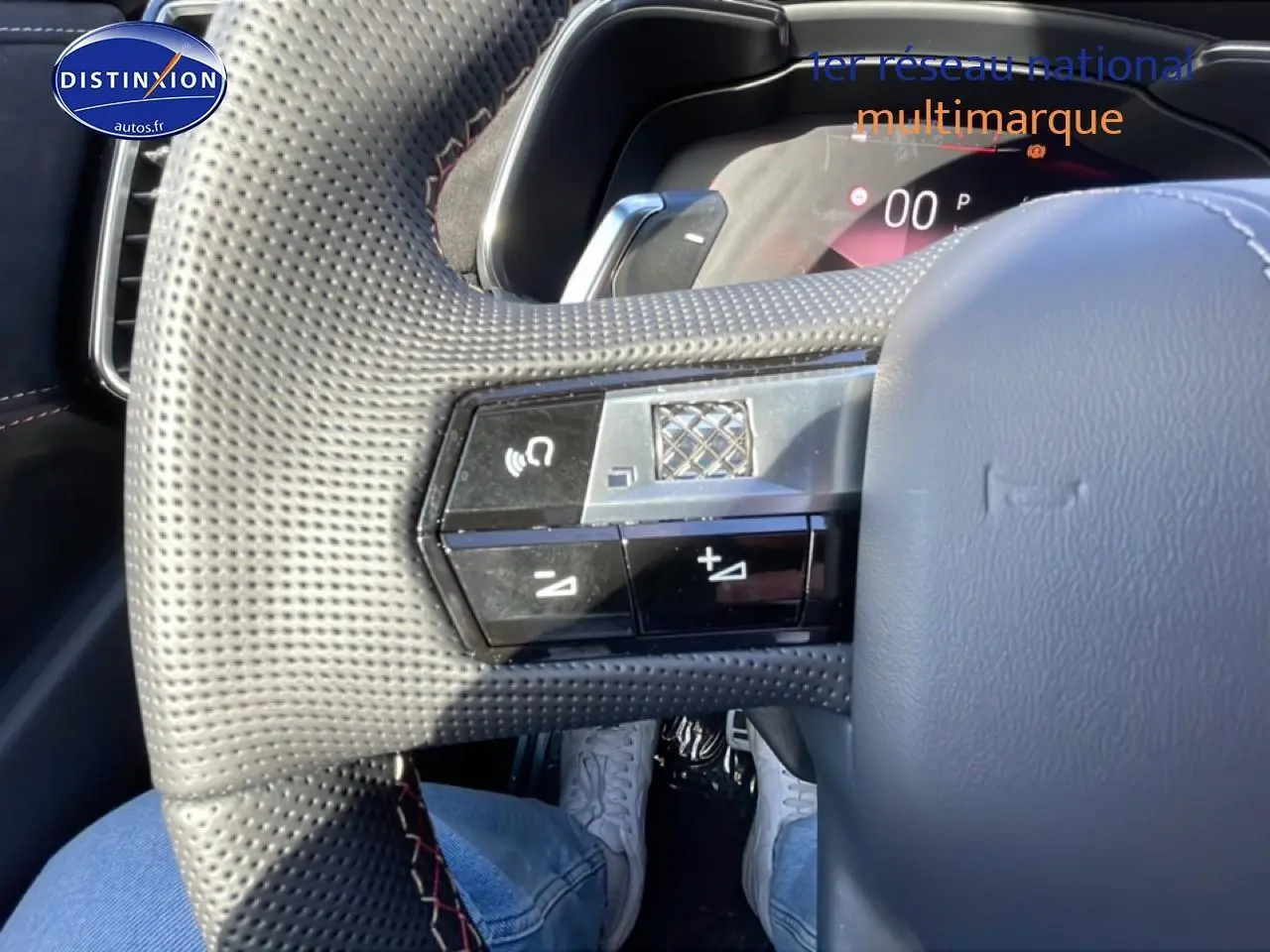 Gros plan sur le volant cuir perforé du DS7 1.5 BlueHDi 130, avec commandes multifonctions et coutures rouges visibles.