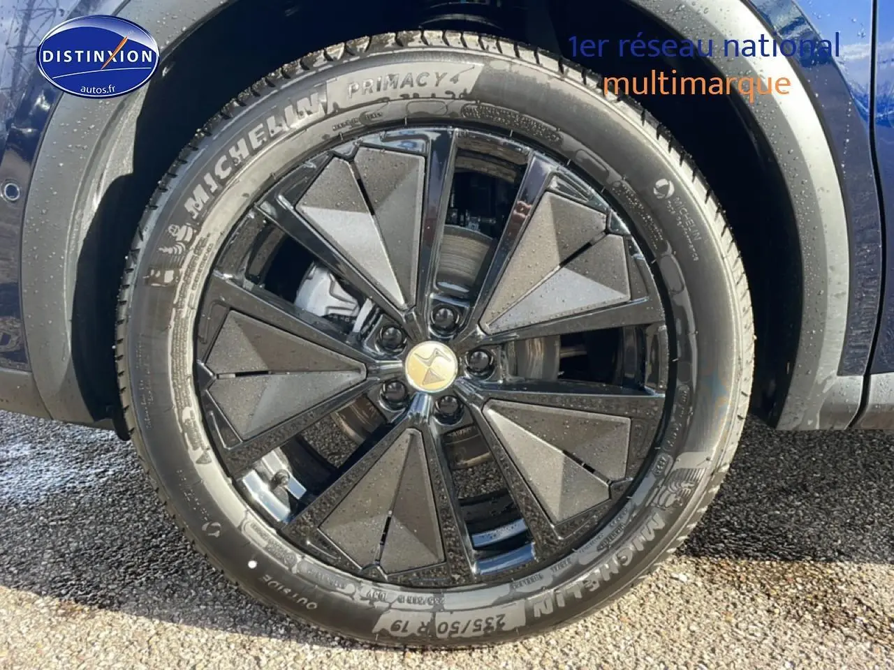 Gros plan sur la jante noire au design géométrique du DS7 bleu, mettant en valeur le pneu Michelin.