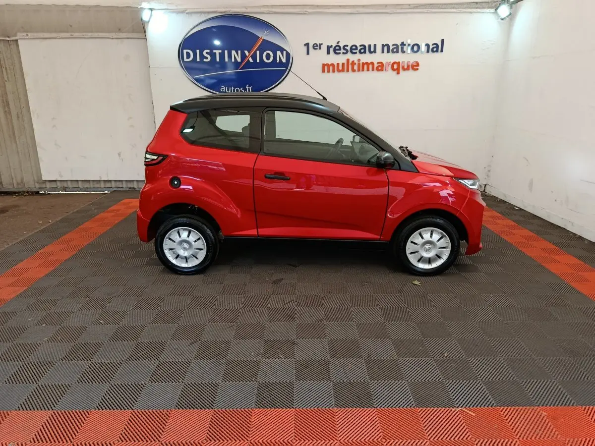Vue de profil côté gauche d'une Aixam Ambition 0.5 City Crossline Pack rouge 2024 avec toit noir en intérieur showroom.