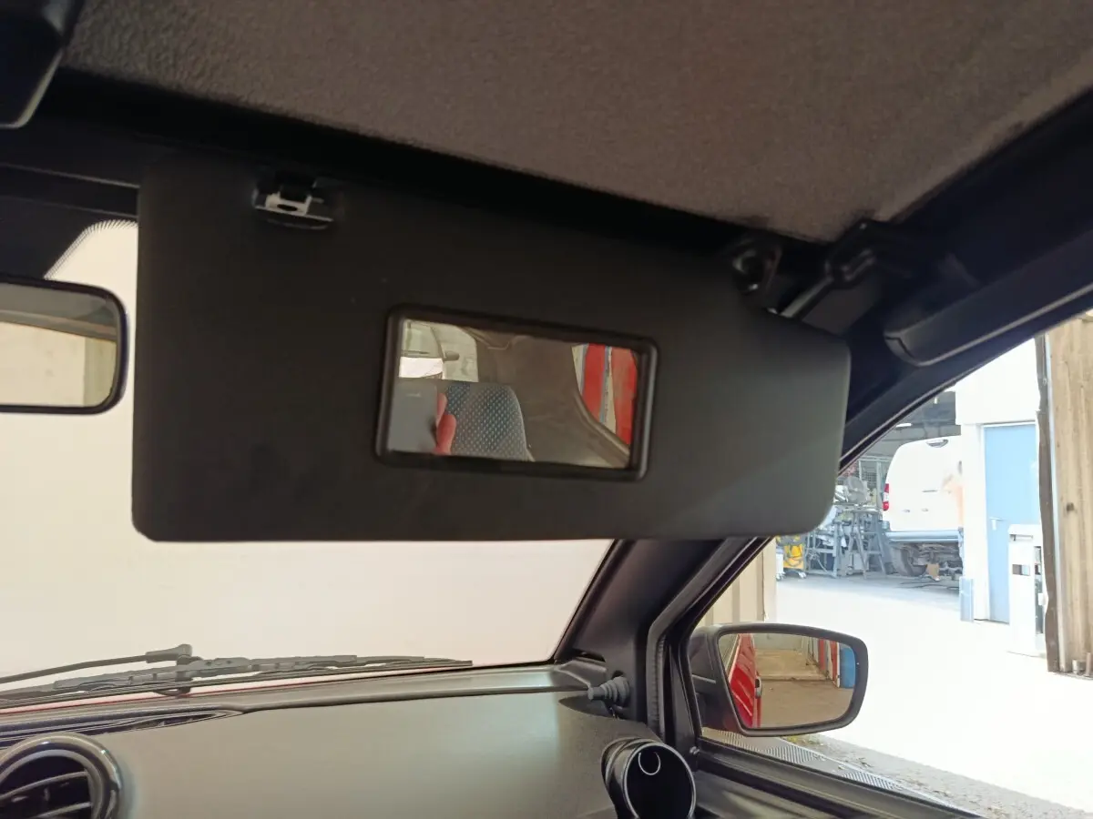 Vue intérieure côté conducteur de l'AIXAM Ambition 0.5 City Crossline Pack 2024 rouge, avec pare-soleil et rétroviseur extérieur visible.