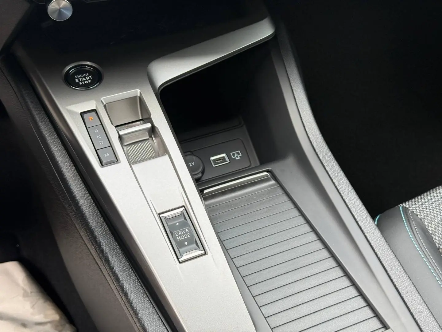 Gros plan sur la console centrale argentée avec sélecteur de boîte auto et bouton Drive Mode dans une Peugeot 308 SW rouge.