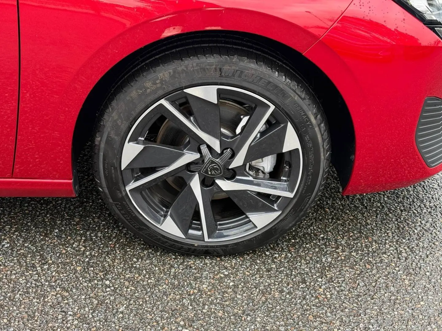 Gros plan sur la roue avant gauche avec jante alu noire et argentée du Peugeot 308 SW rouge Elixir.