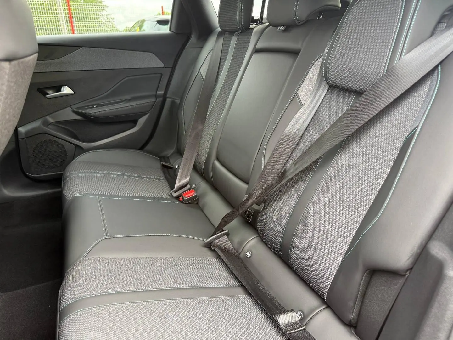 Vue côté gauche de la banquette arrière en tissu et cuir noir avec ceintures attachées du Peugeot 308 SW 2025.