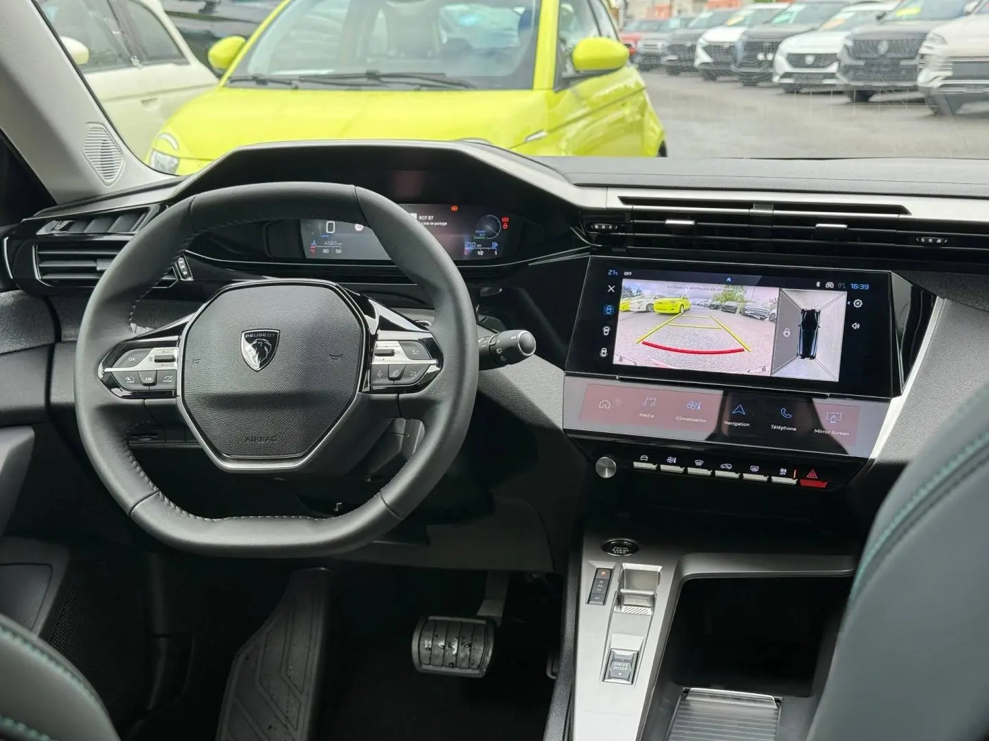Vue intérieure centrée sur le volant et l’écran tactile du tableau de bord d’une Peugeot 308 SW rouge Elixir.