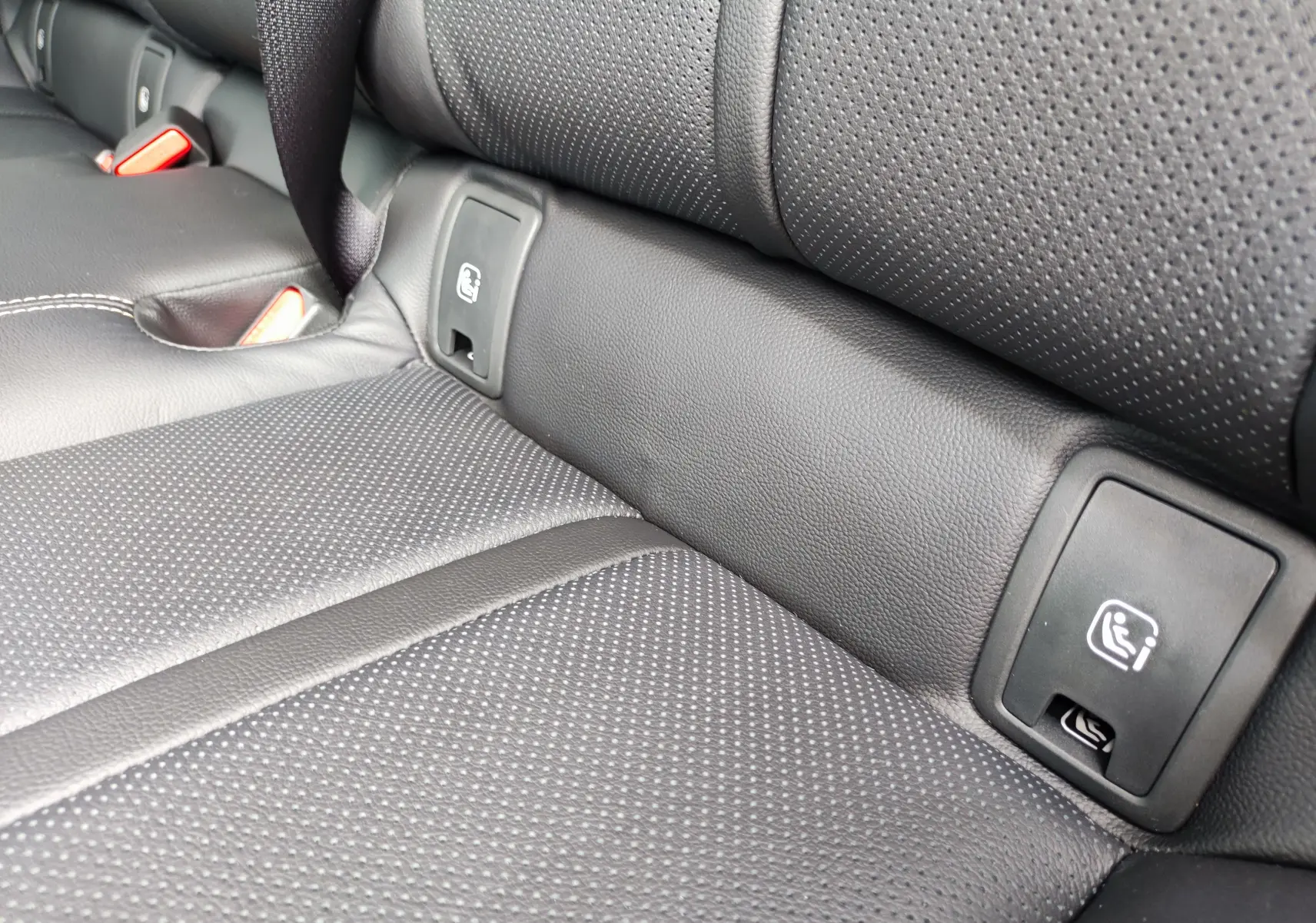 Gros plan sur la banquette arrière en cuir noir perforé du Mazda CX-60 2024 avec ancrages ISOFIX visibles.