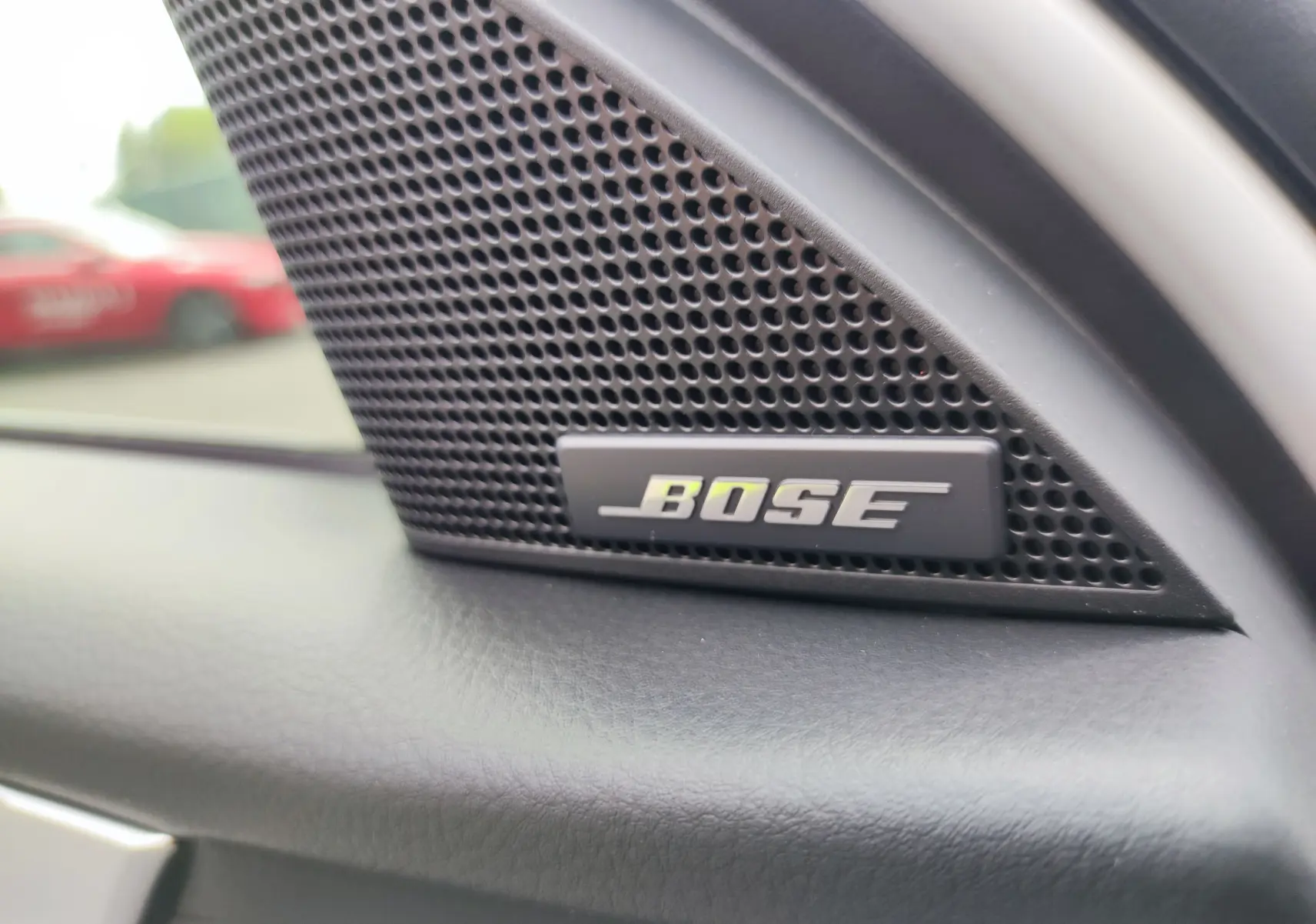 Gros plan sur l'enceinte Bose intégrée à la porte côté gauche du Mazda CX-60 blanc métal 2024.