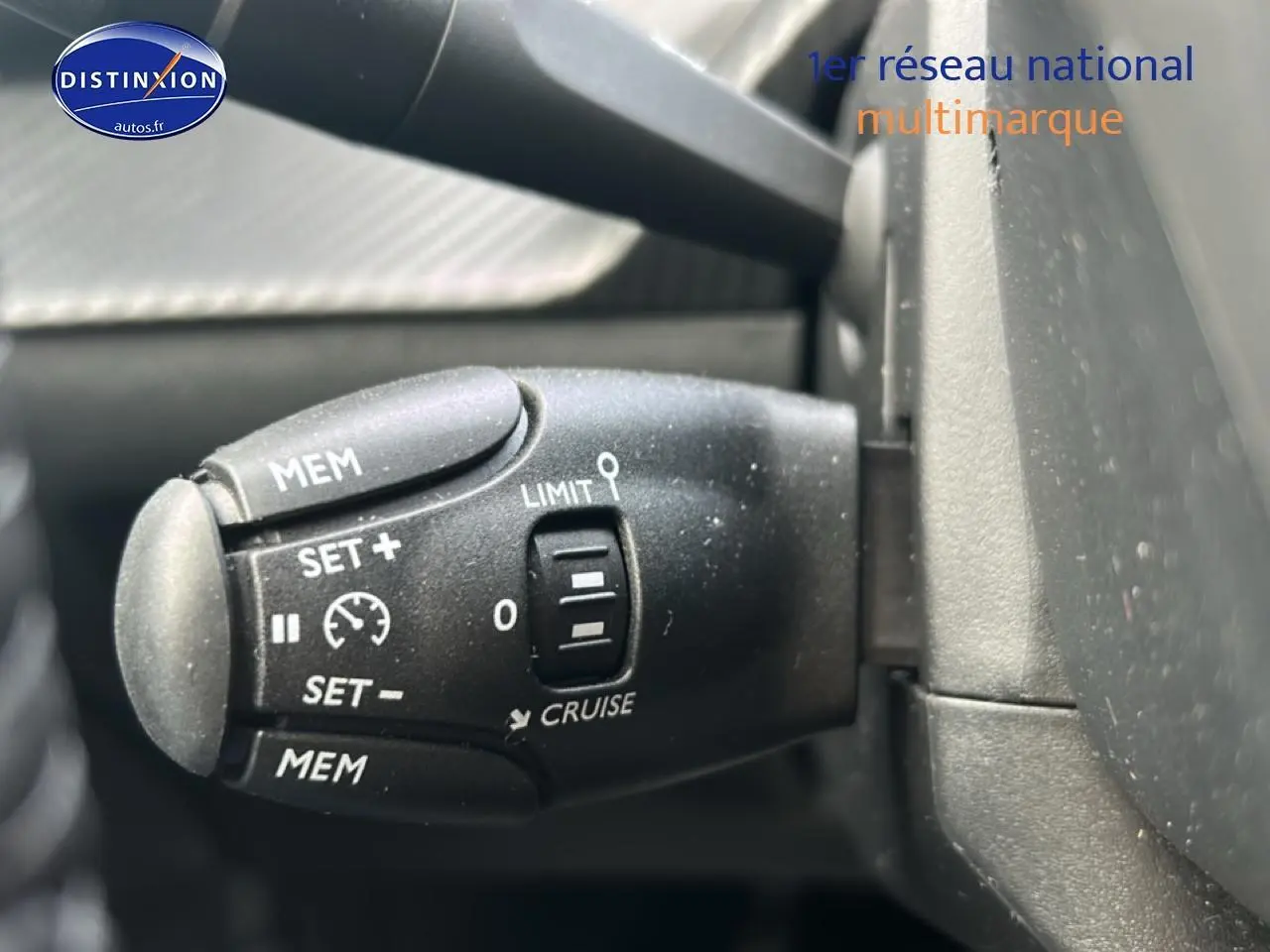 Gros plan sur la commande de régulateur de vitesse noire dans l'habitacle d'une Peugeot 208 gris artense.