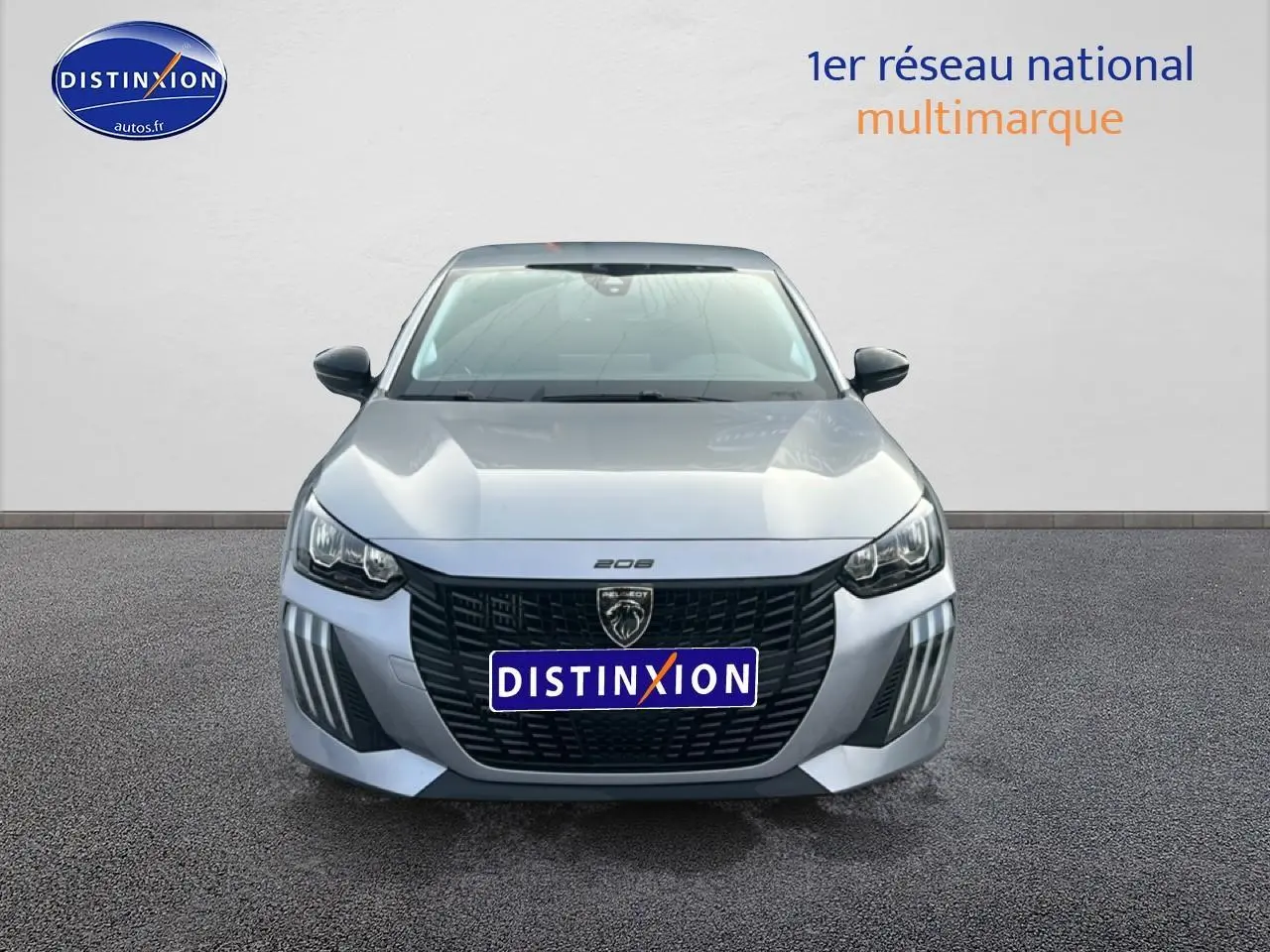 Vue frontale d'une Peugeot 208 gris artense avec calandre noire et phares LED distinctifs.