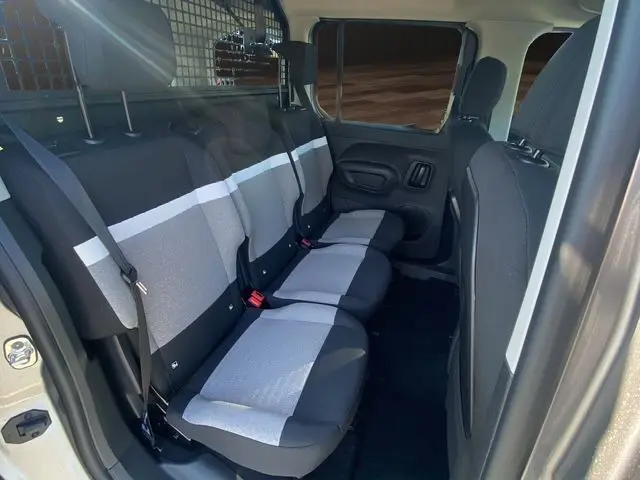 Vue intérieure côté gauche des sièges arrière gris clair et noir du Citroën Berlingo 2025 avec cloison de séparation et ceintures de sécurité.