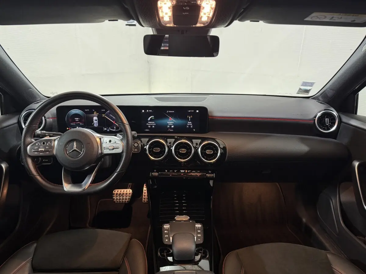 Vue intérieure frontale du tableau de bord et volant cuir alu de la Mercedes Classe A 200 AMG Line 2021, avec écrans numériques larges.