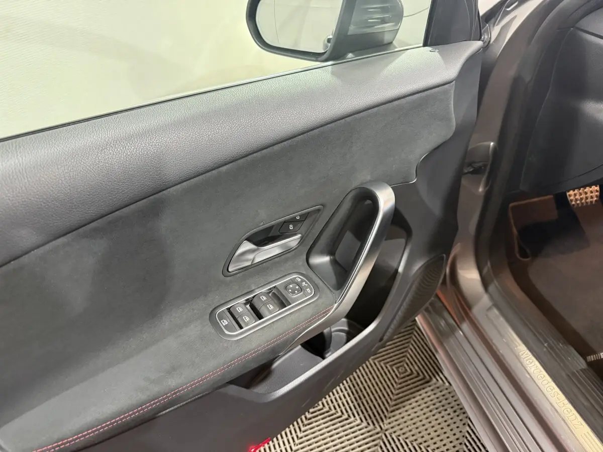 Détail de la porte avant gauche gris foncé de la Mercedes Classe A 200 AMG Line avec commandes des vitres et poignée alu.