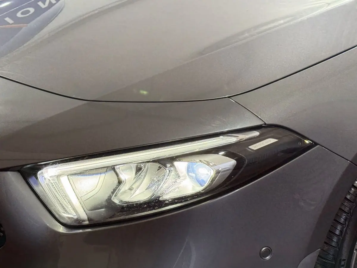 Gros plan sur le phare avant droit d’une Mercedes Classe A 200 AMG Line gris foncé, mettant en valeur les détails LED.