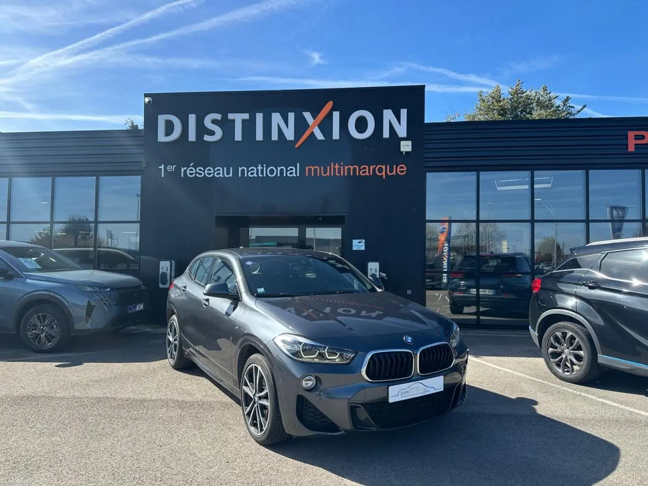 BMW X2 gris foncé vue 3/4 avant droit, avec jantes alliage 19 pouces et calandre double haricot distinctive.