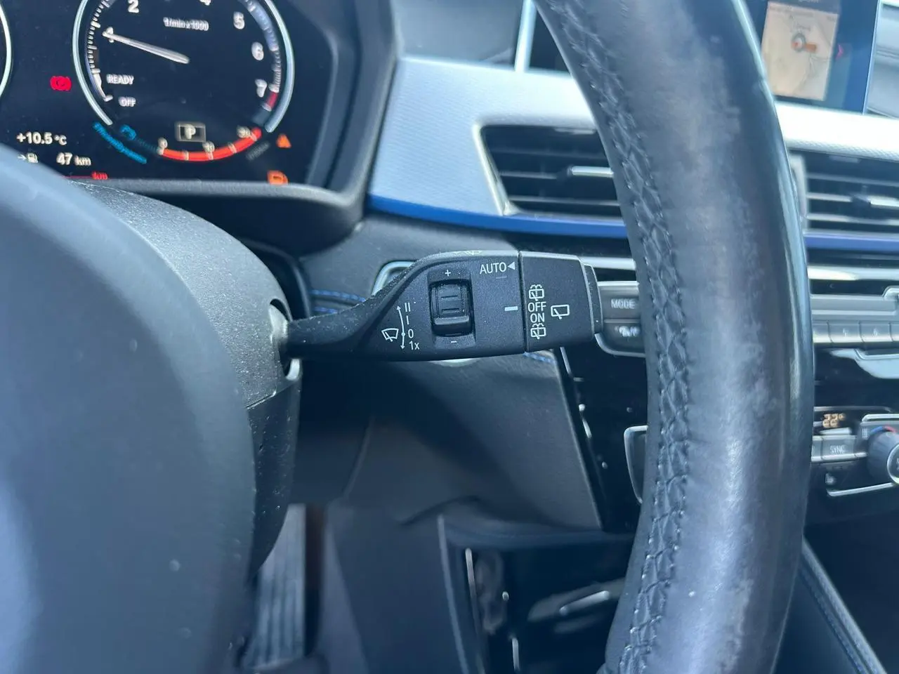 Gros plan sur la commande d’essuie-glace à gauche du volant cuir noir dans l’habitacle gris et bleu d’une BMW X2 2020.