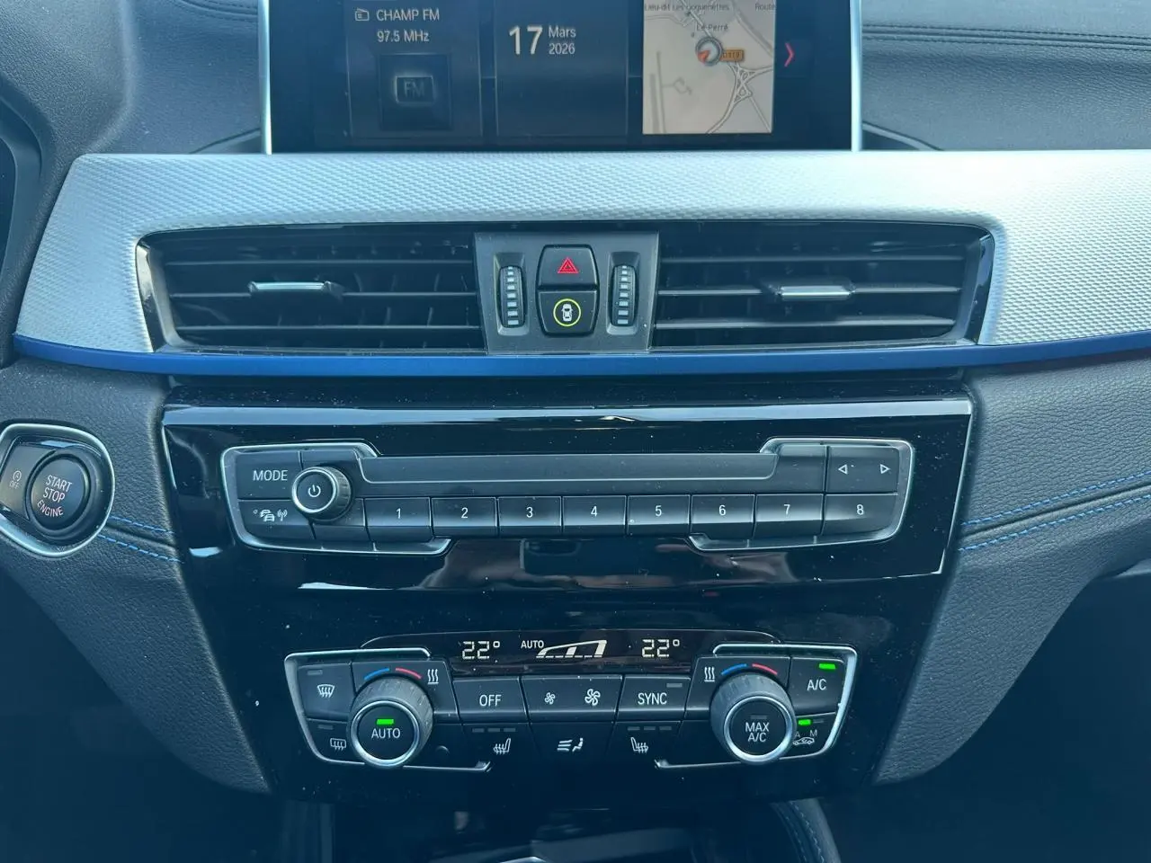 Vue centrée sur la console centrale intérieure du BMW X2 gris foncé, avec commandes climatisation et écran multimédia.
