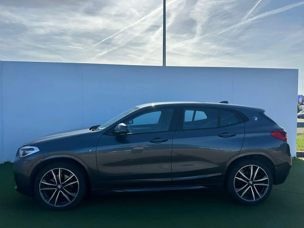 Vue de profil côté gauche d'un BMW X2 gris foncé avec jantes alliage 19 pouces et logo M Sport sur custode.