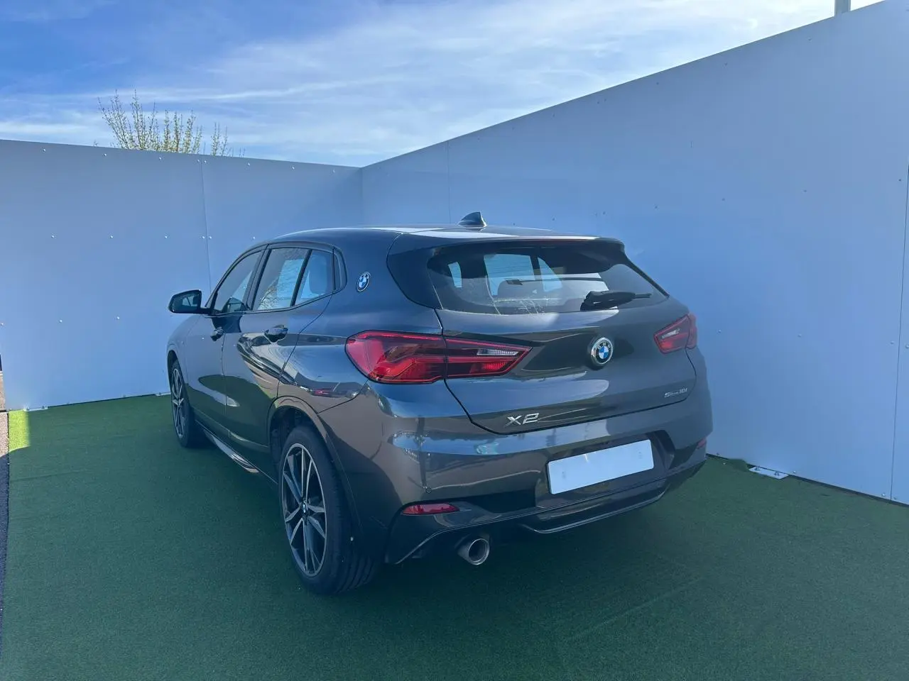 BMW X2 gris foncé vue 3/4 arrière droit, avec jantes alliage 19 pouces et logo BMW sur custode.