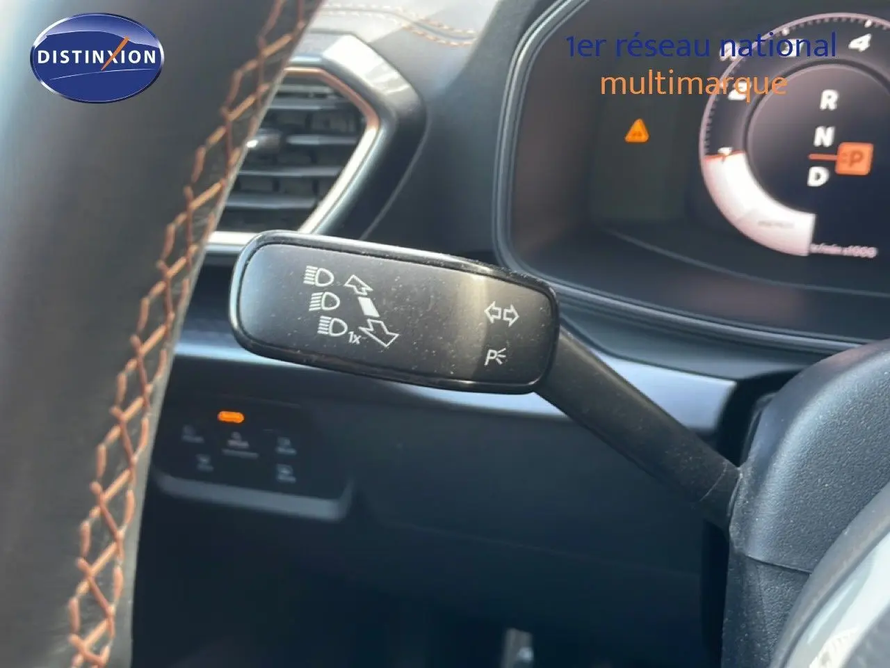 Gros plan sur la commande de clignotants à gauche du volant d’un CUPRA Formentor blanc neige métal, tableau de bord numérique visible.